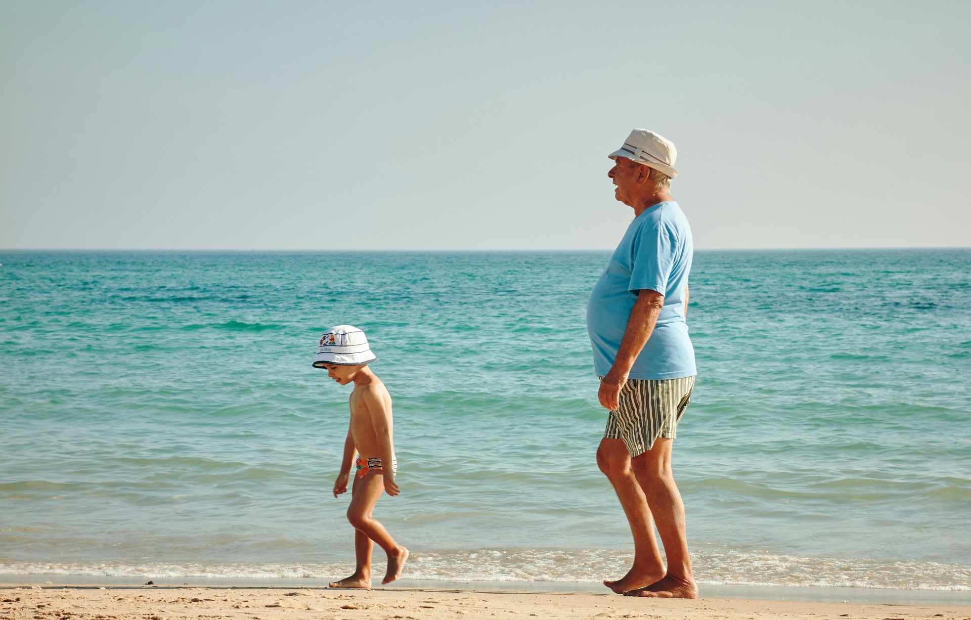 Grandfather and grandchild walking together on the beach